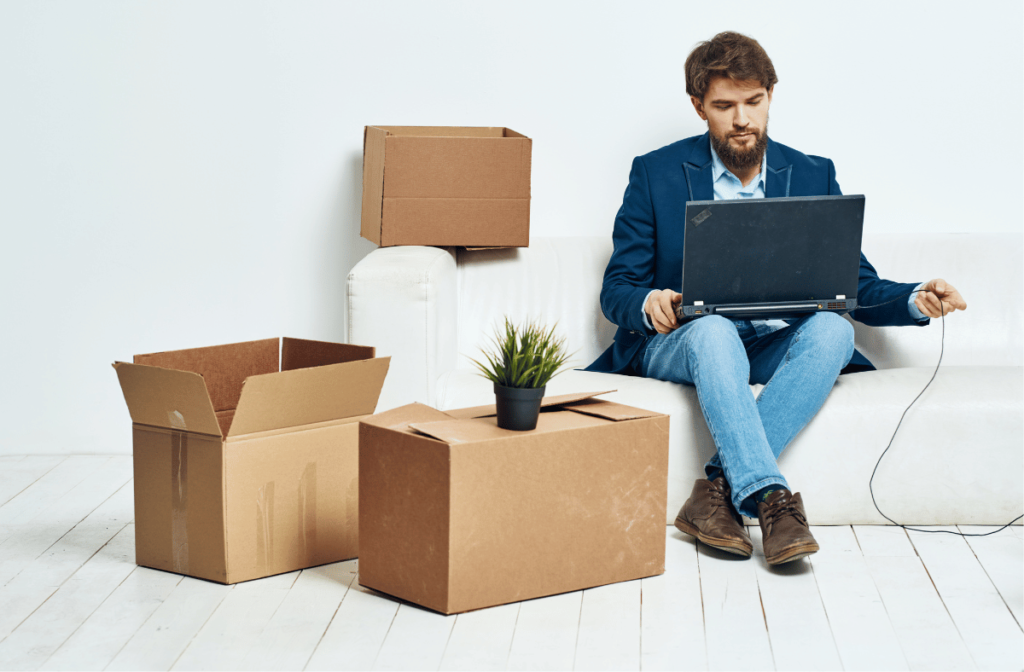 Digital Transformation of Trade - young businessman with laptop surrounded by boxes