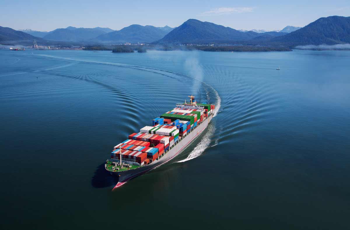 Export Factoring - Supply Chain - Container ship on the water with mountains in background