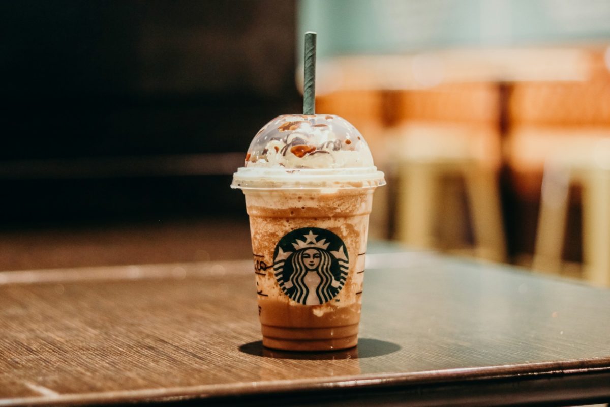 Starbucks Frappuccino on a wooden table inside a cozy coffee shop with blurred background