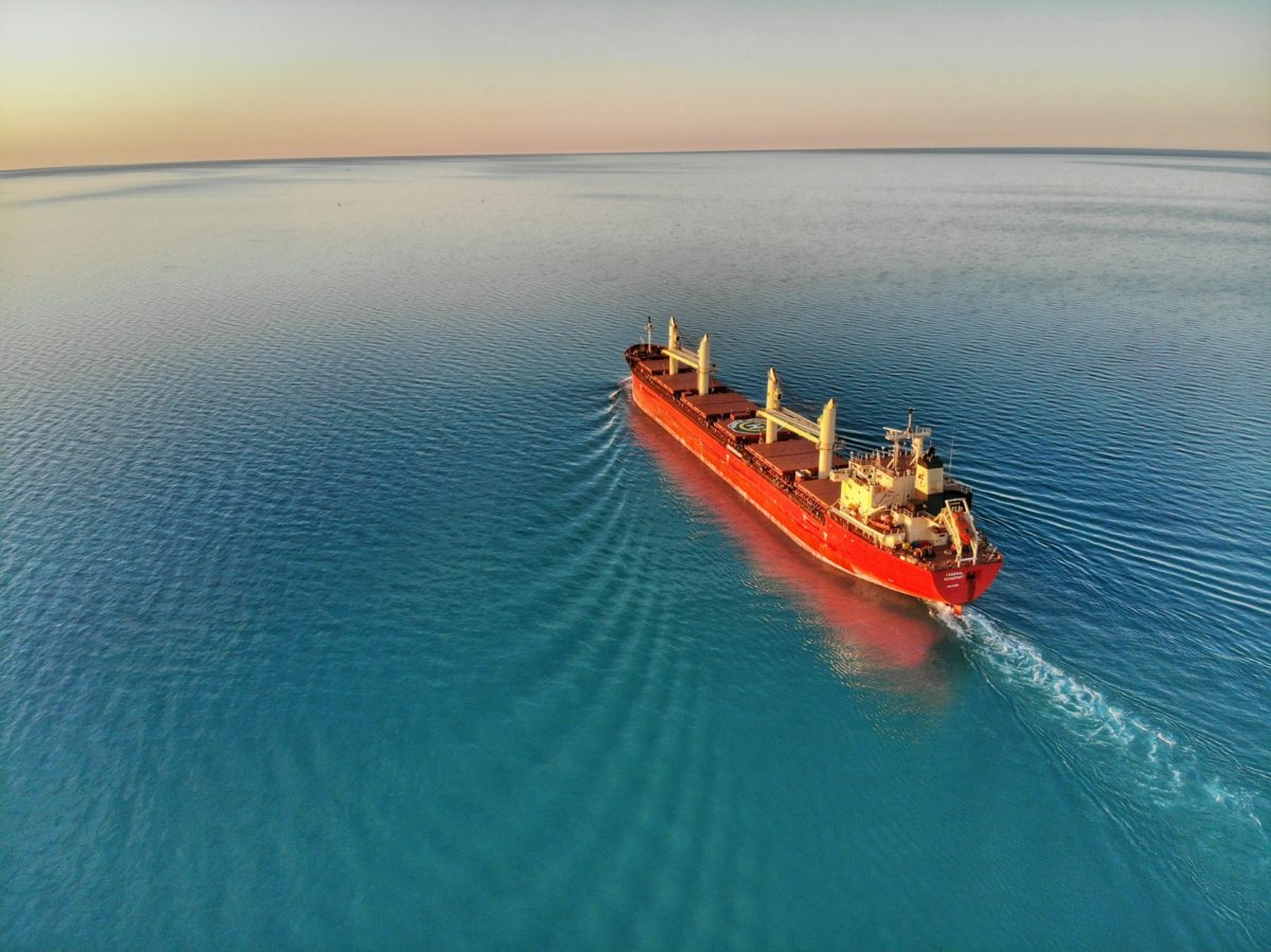 Large cargo ship sailing on calm blue waters during a serene sunset, symbolizing maritime transportation and global trade