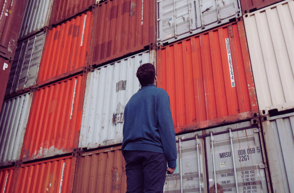 Concept for man considering exporting as a business model - man looking up at stacked cargo containers