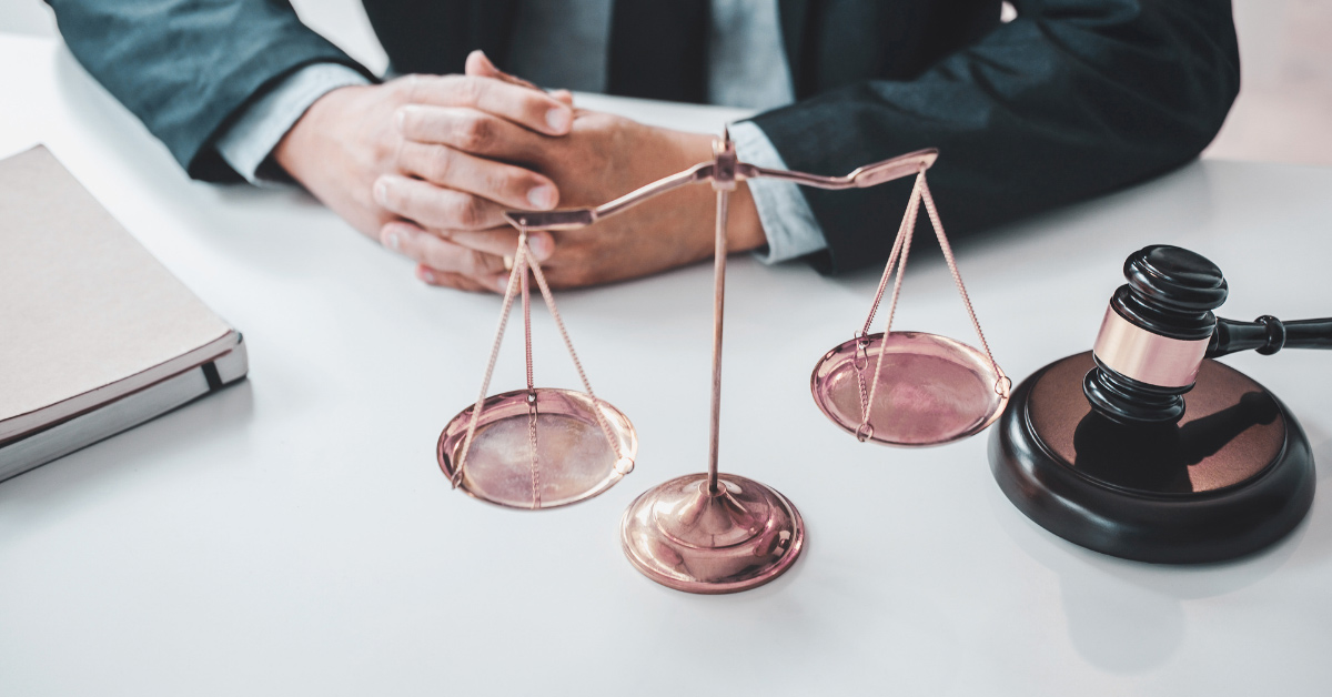 Scales of justice and gavel on desk with businessman seated symbolizing ethics and integrity