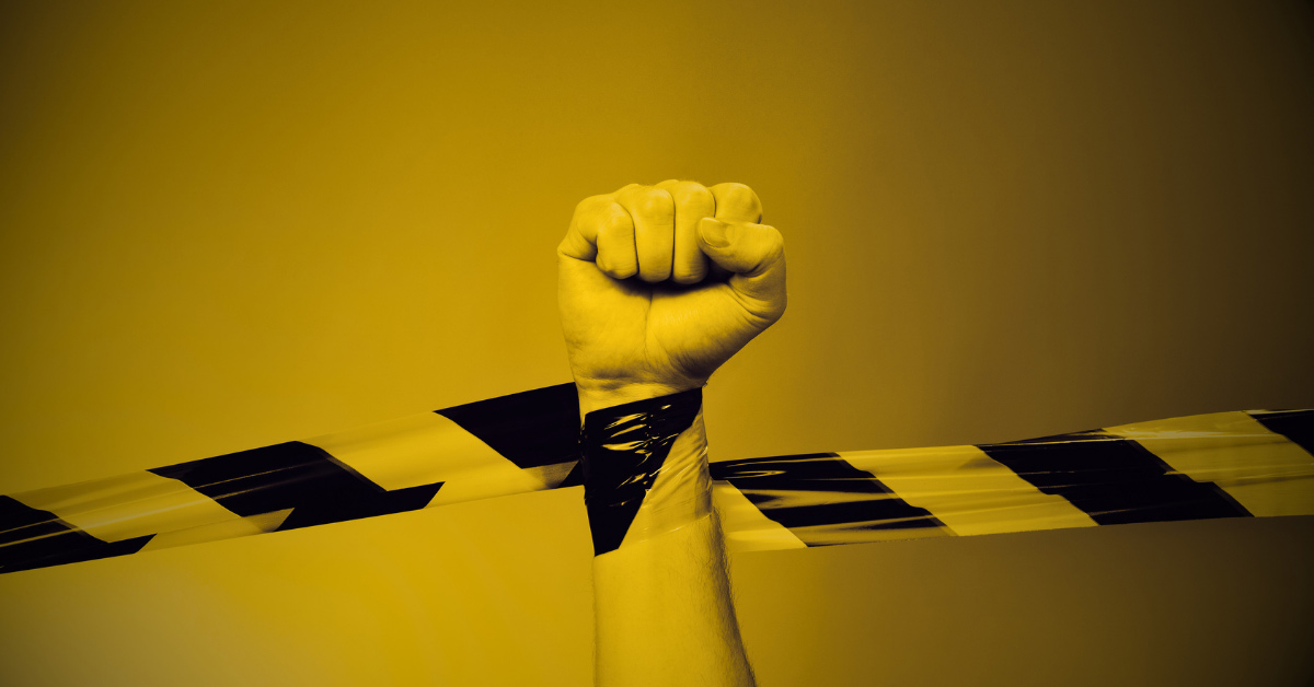hand punching through caution tape symbolizing overcoming market barriers